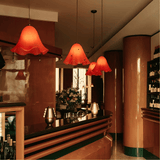 Bar area with red pendant lights, floral arrangement, and bottles.