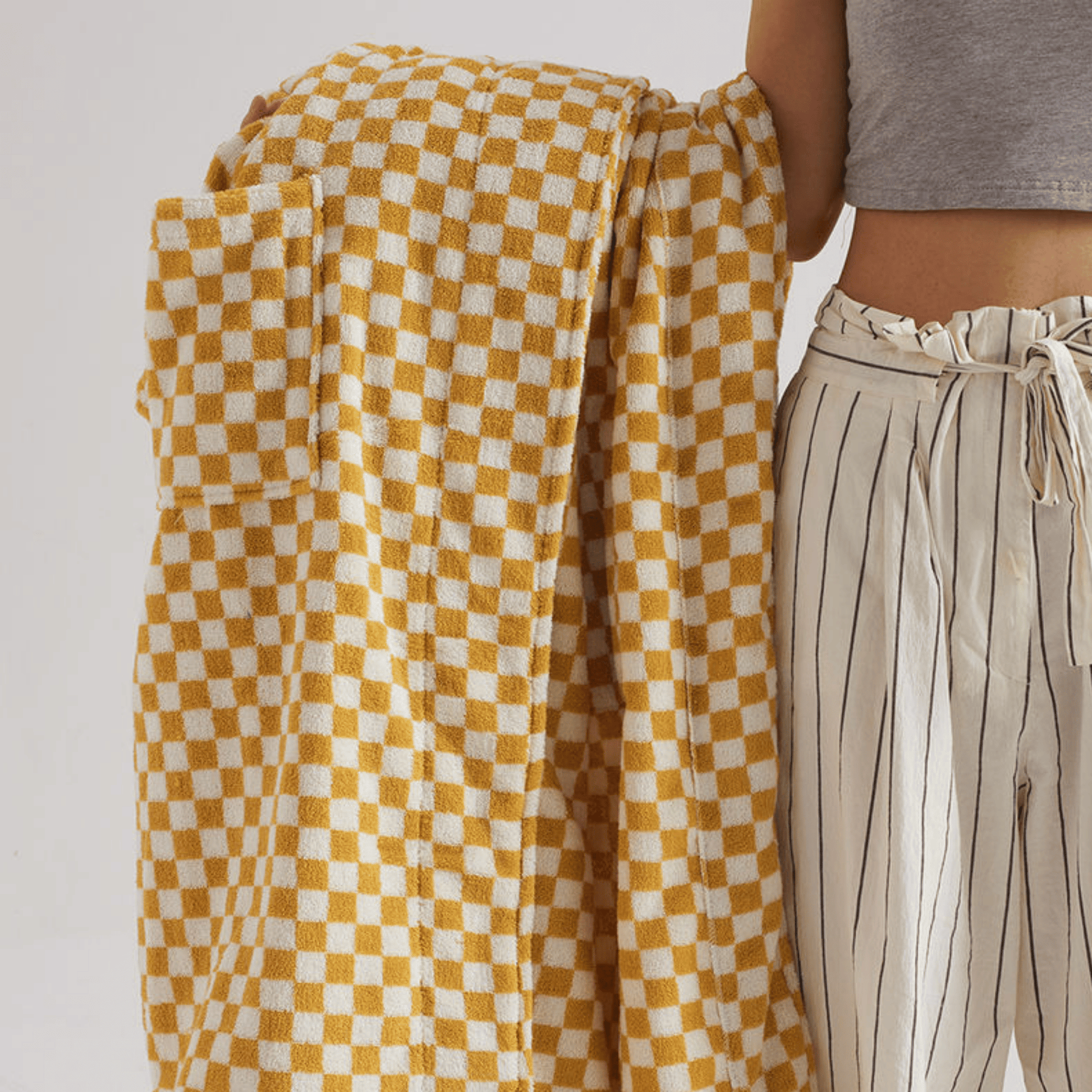 Person holding a yellow and white checkered towel with a neutral background