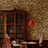 Vintage room with wooden bookshelf, floral wallpaper, and red lamp.
