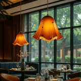Dining area with orange pendant lights and a view of trees outside.
