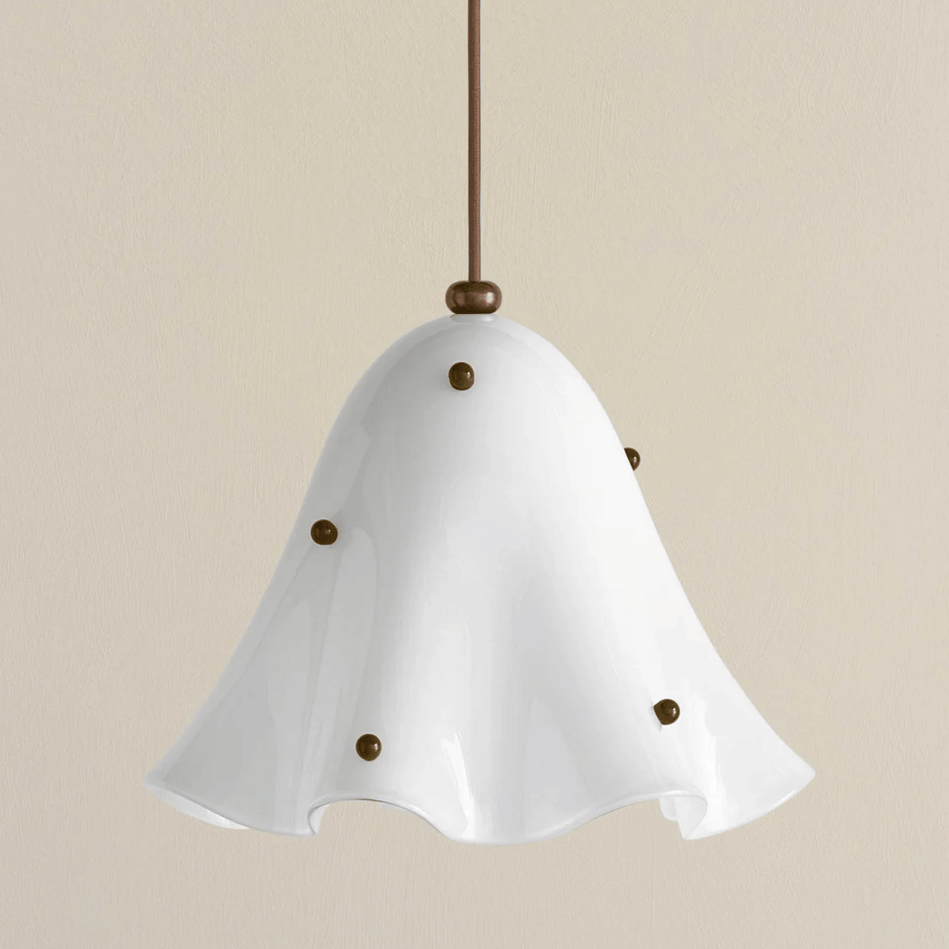 White pendant light with brass accents on a beige background