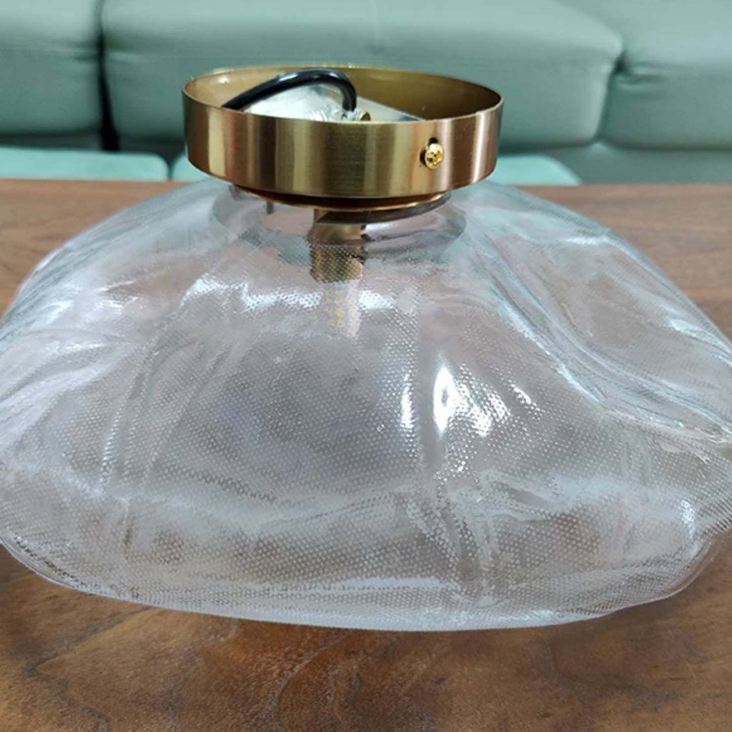 Clear glass lampshade with gold metal fixture on a wooden surface