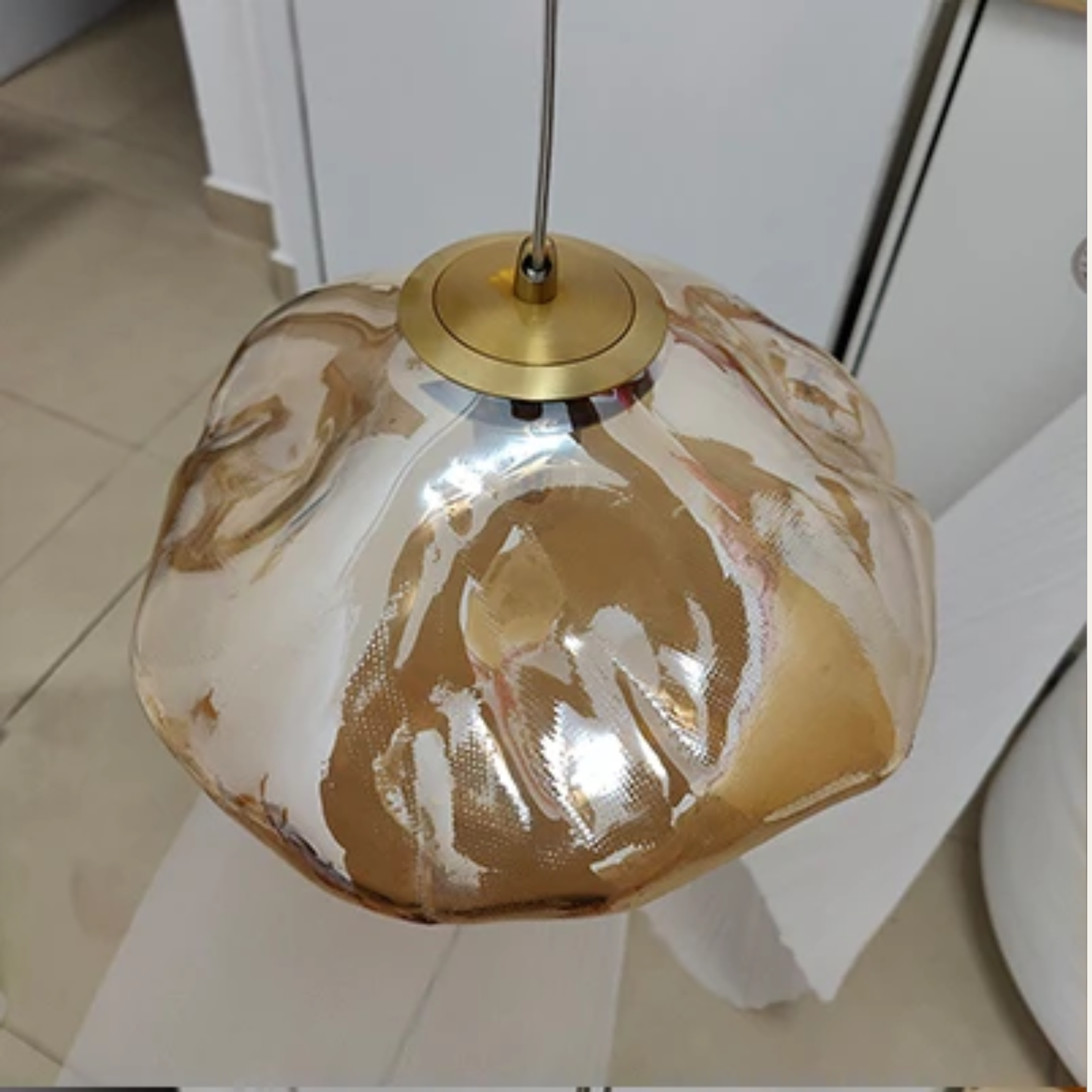 Decorative pendant light with gold and white marbled design on a neutral background