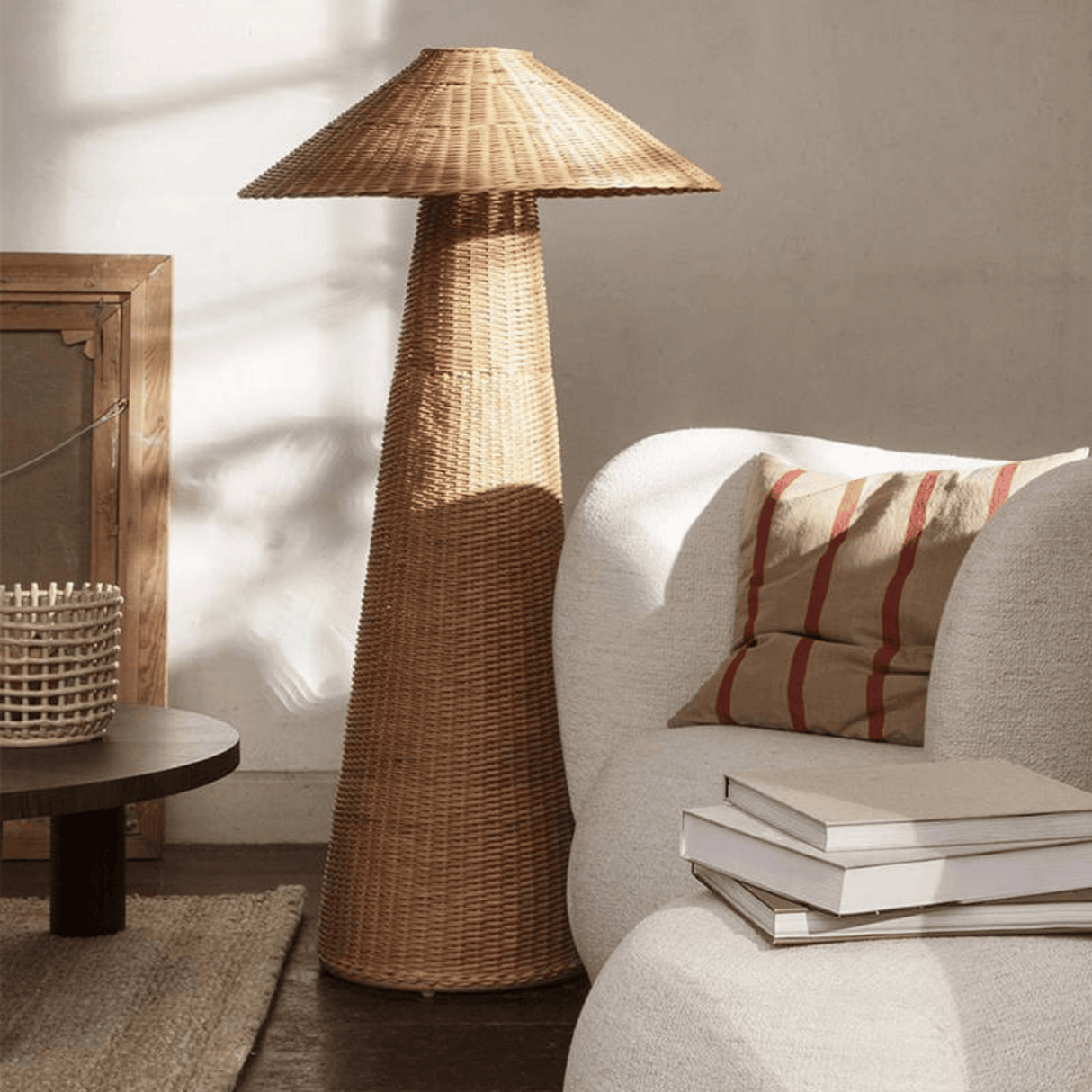 Wicker floor lamp in a living room setting with a sofa and books.