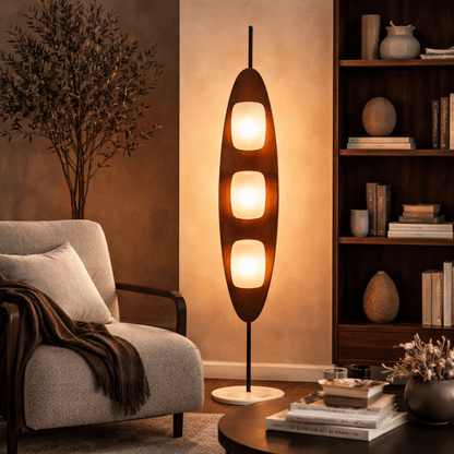 Modern floor lamp in a living room setting with a chair and bookshelf.