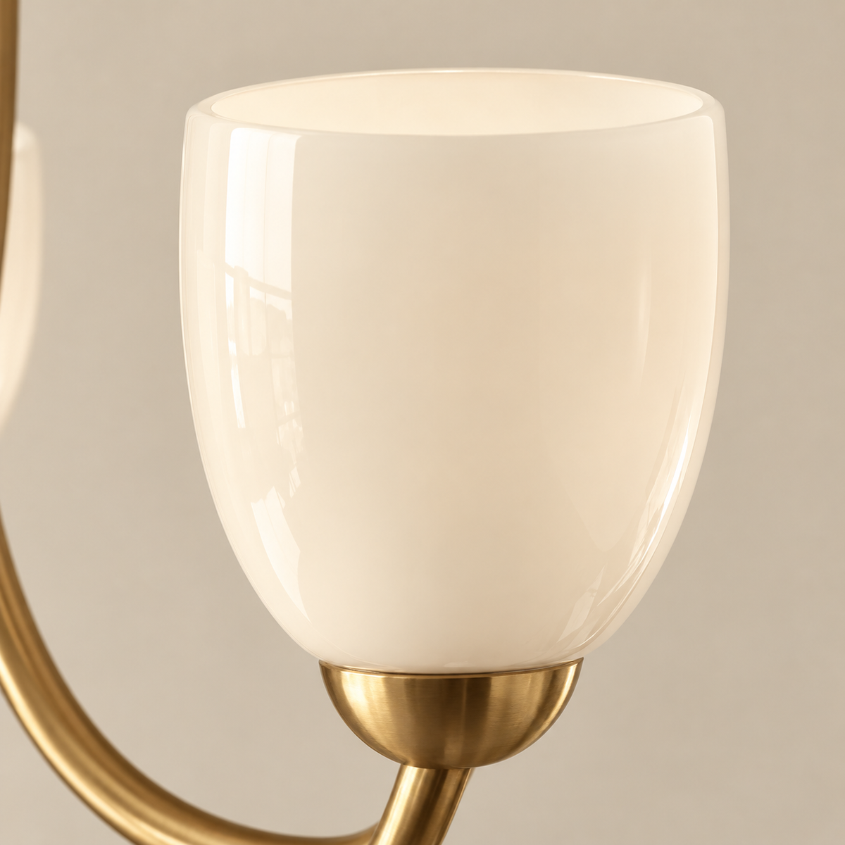 Close-up of a modern wall sconce featuring a glossy, rounded white glass shade mounted on a brushed gold metal stem.