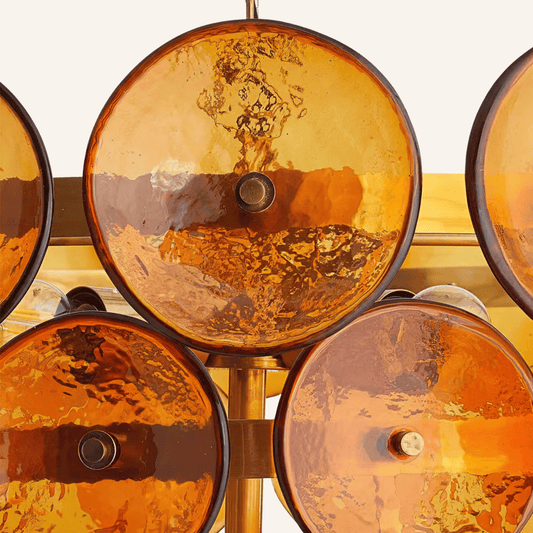 Close-up of amber glass light fixtures with gold metal accents on a white background