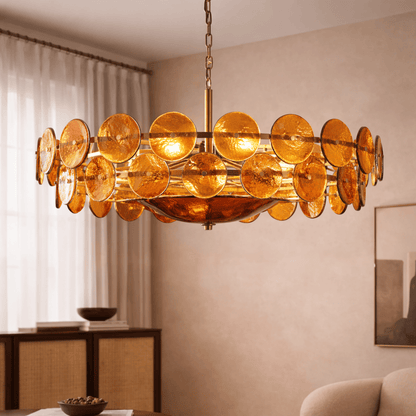 Gold circular chandelier in a room with beige walls and a window.