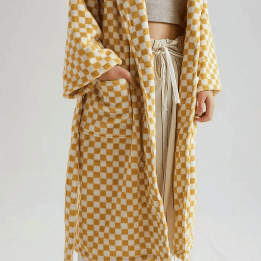 Person wearing a yellow and white checkered robe over a neutral outfit on a plain background