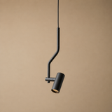A modern black pendant light with a curved, bent metal arm and a cylindrical shade, shown hanging against a solid beige background.