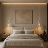 A minimalist bedroom scene featuring a neatly made bed with beige linens, two matching pillows, a large textured beige wall art piece, and two modern white pendant lights hanging on either side of the bed.