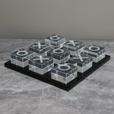 Transparent tic-tac-toe board with Xs and Os on a gray surface