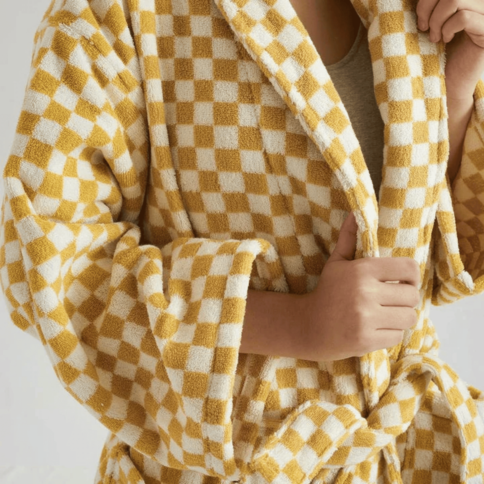 Person wrapped in a yellow and white checkered blanket on a plain background