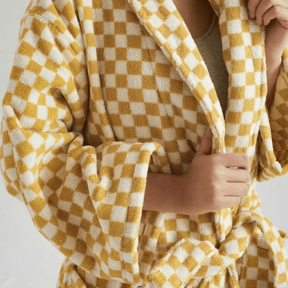 Person wrapped in a yellow and white checkered blanket on a plain background