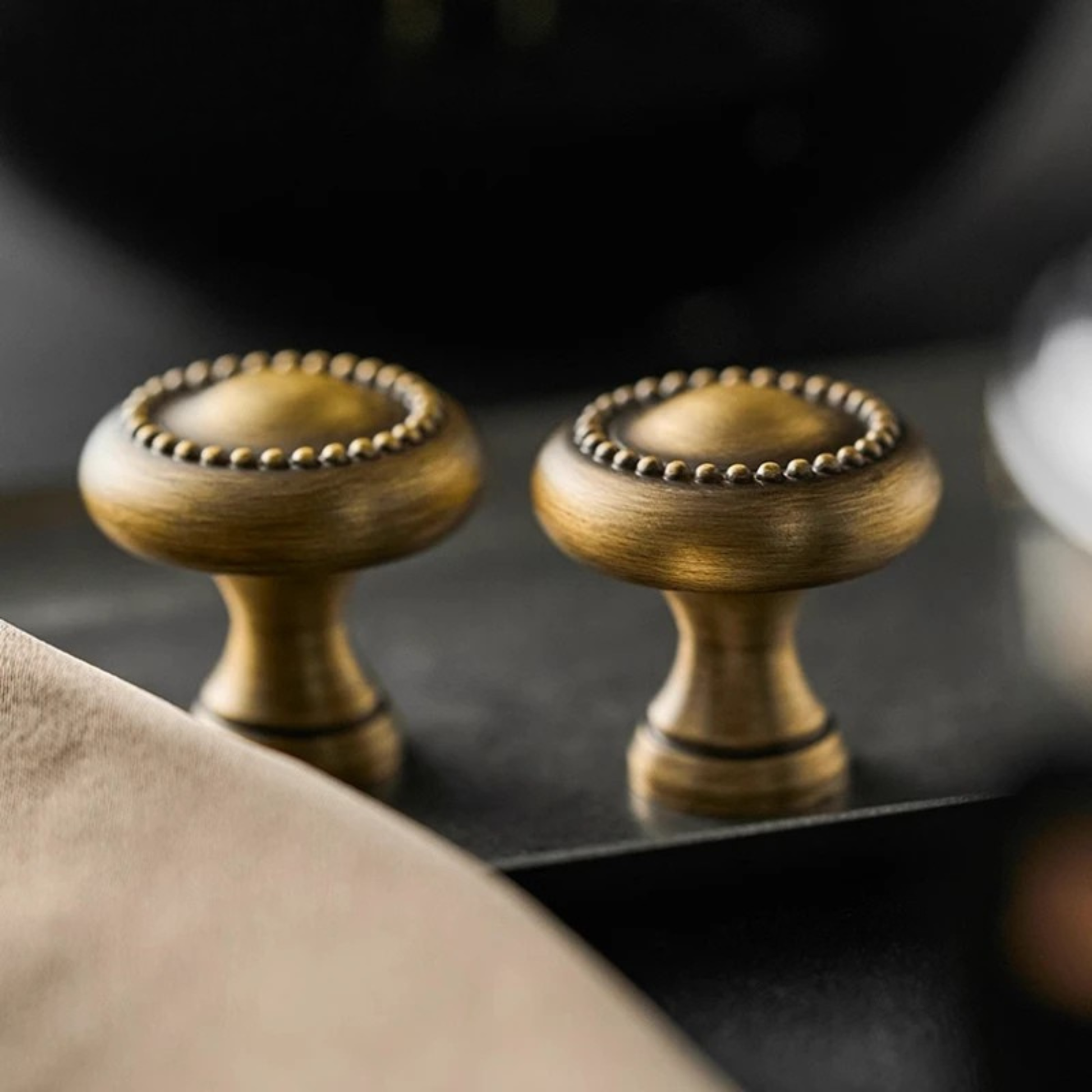 A single brass cabinet knob with decorative edging, placed near a sink.
