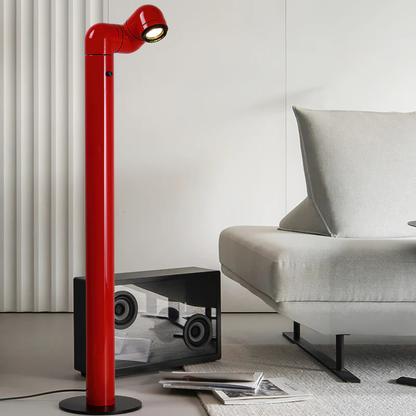 A red floor lamp positioned next to a window, casting light on the surrounding space.