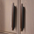Pair of long bronze and wood handles installed vertically on a light wooden cabinet door