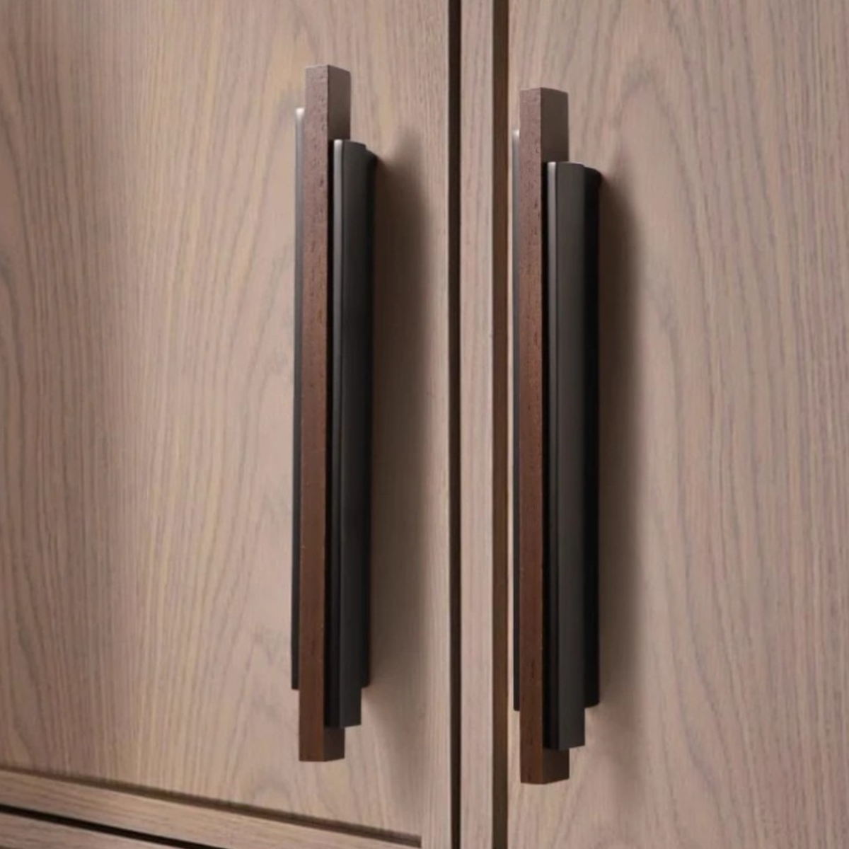 Pair of long bronze and wood handles installed vertically on a light wooden cabinet door
