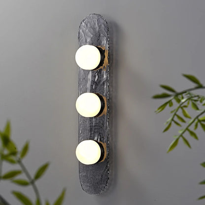 single bulb sconce with brass mount on dark raindrop textured backplate