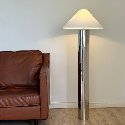 modern chrome floor lamp next to a woven cane chair and a mirrored panel on the floor