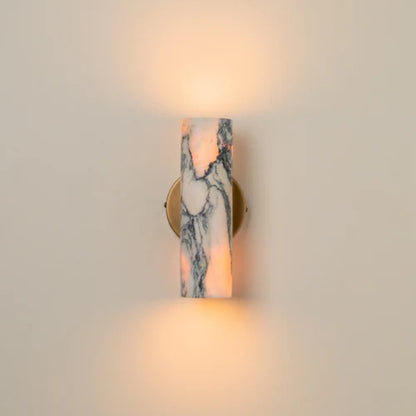 Modern marble wall sconce with soft up-and-down lighting mounted on a neutral beige wall.
