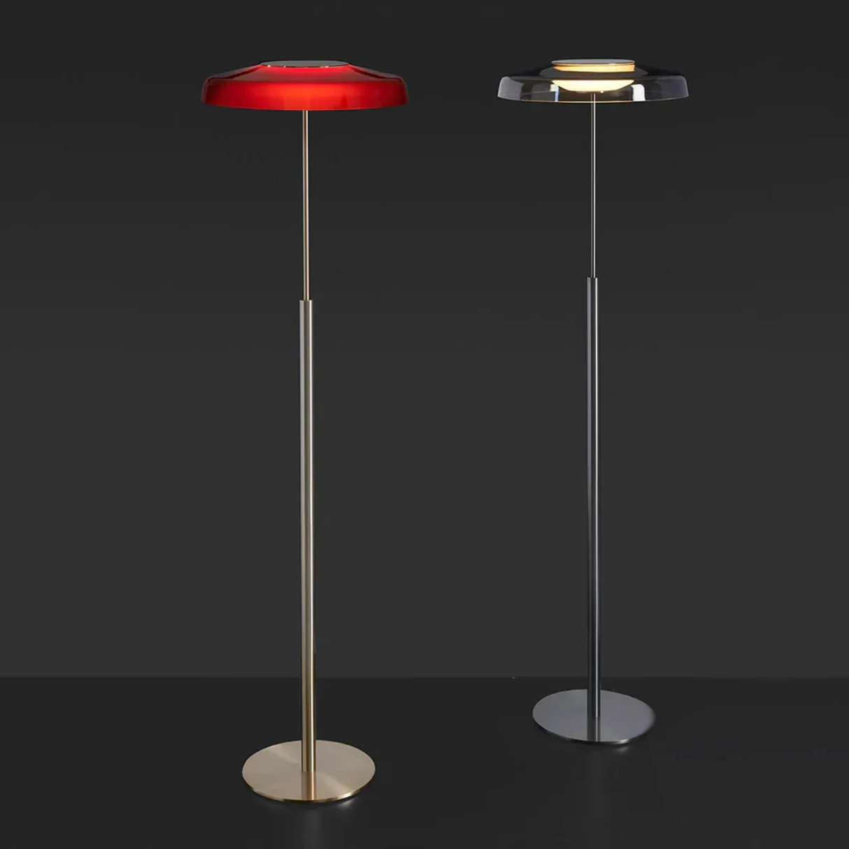 Two floor lamps—one silver, one red—standing side by side against a dark background for product comparison.