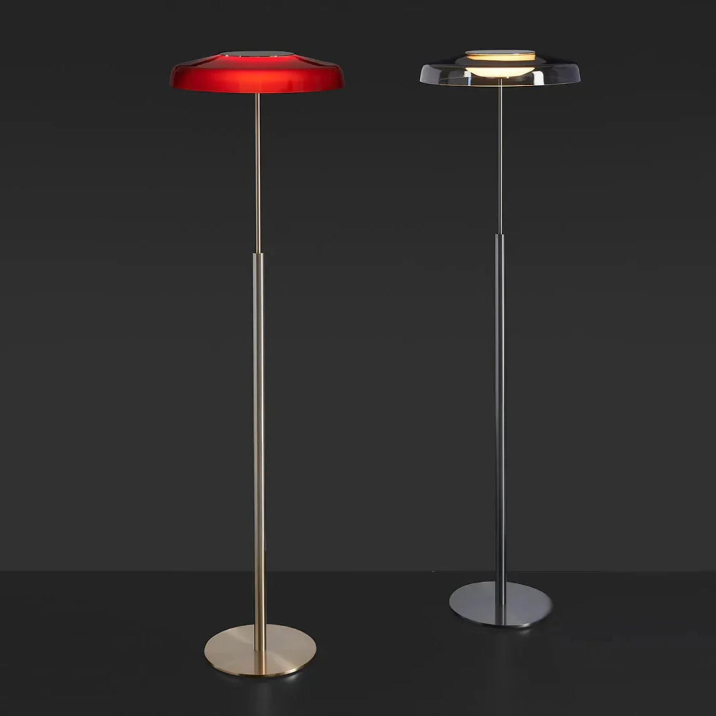 Two floor lamps—one silver, one red—standing side by side against a dark background for product comparison.