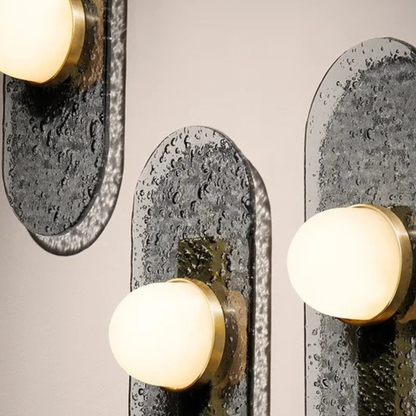 trio of wall sconces showing raindrop textured glass behind warm dome bulbs