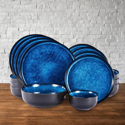 A full blue dinnerware set including plates and bowls arranged neatly against a light stone background.