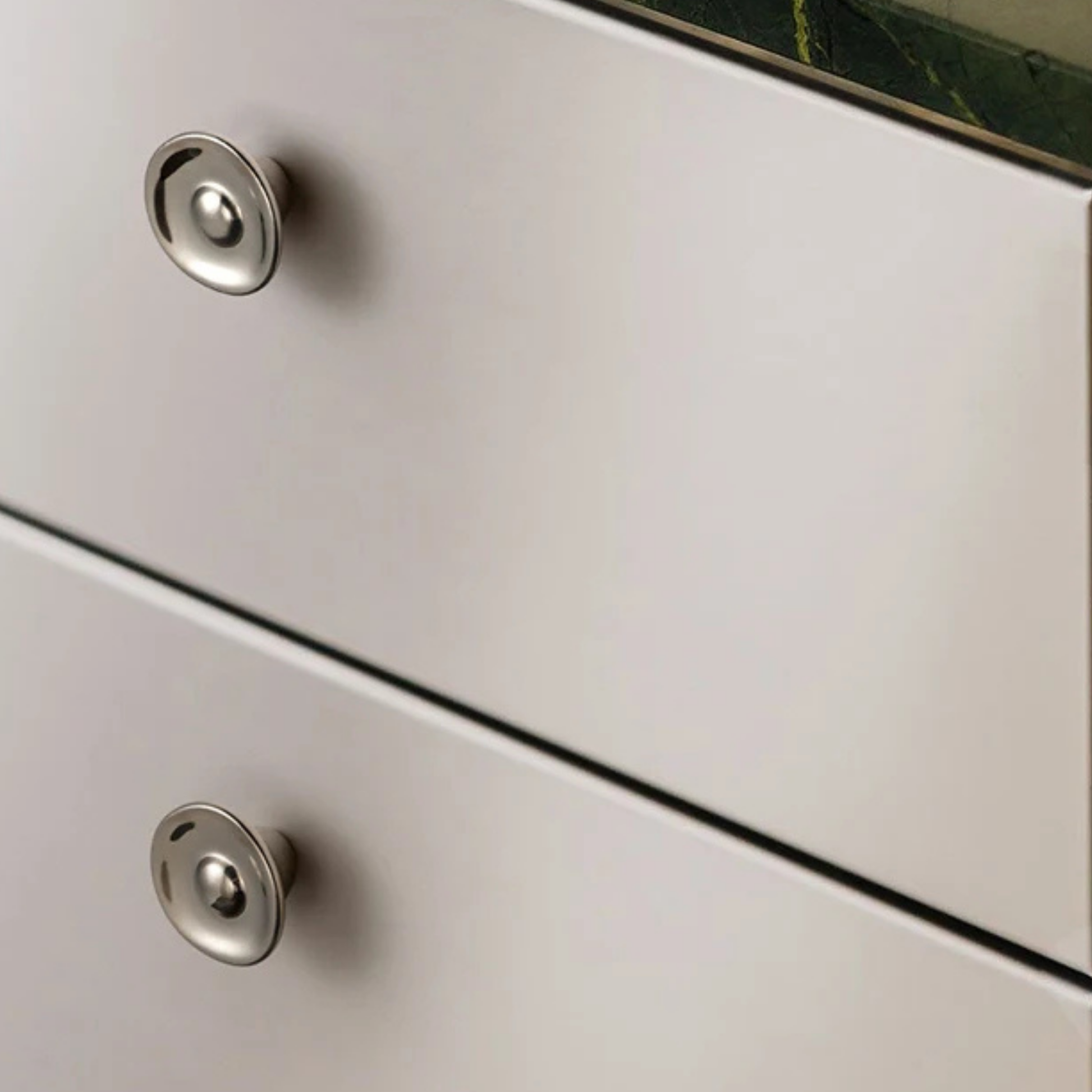 Polished dome-style metal knobs installed on light-colored modern drawers