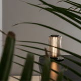 Decorative lamp on a table with plant leaves in the foreground