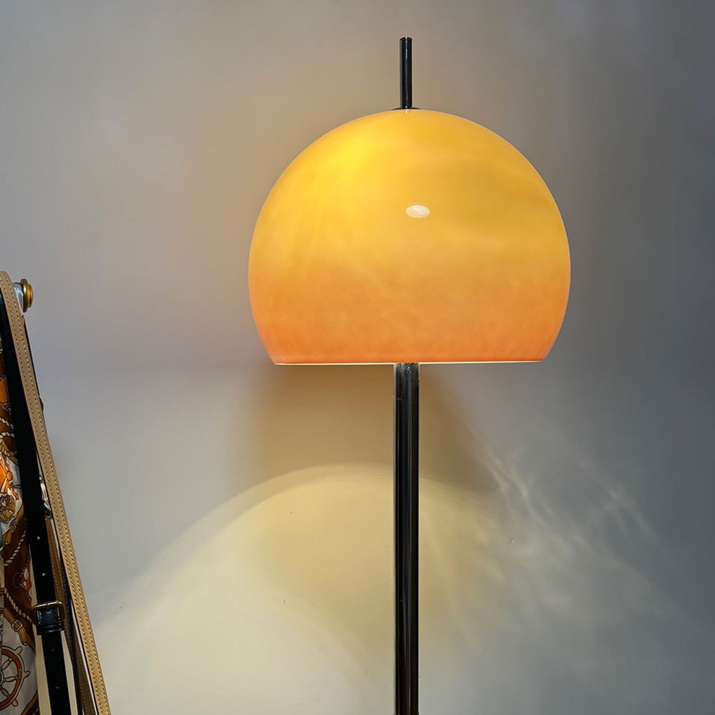A floor lamp with a yellow globe-shaped shade standing next to a plant, creating a calm atmosphere in a living room.