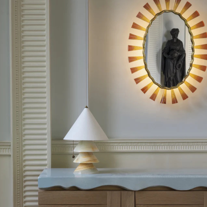Cone-shaded onyx lamp displayed on a blue stone-top cabinet beneath a glowing sunburst mirror.