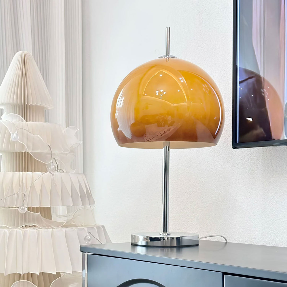 Another view of the Orange  globe lamp on a table, highlighting its clean, modern design with a polished metal base.