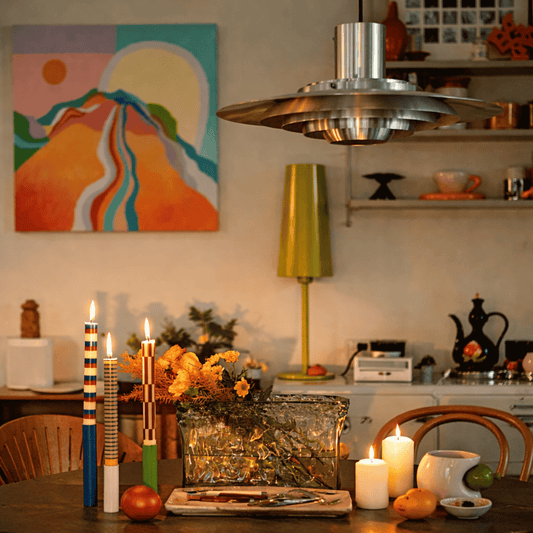 Dining area with candles, a vase of flowers, and a colorful abstract painting on the wall.