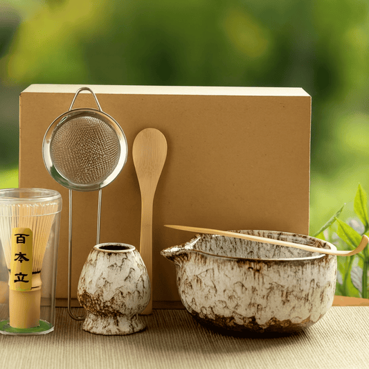 Tea-making set with a wooden spoon, strainer, and ceramic bowls on a blurred green background