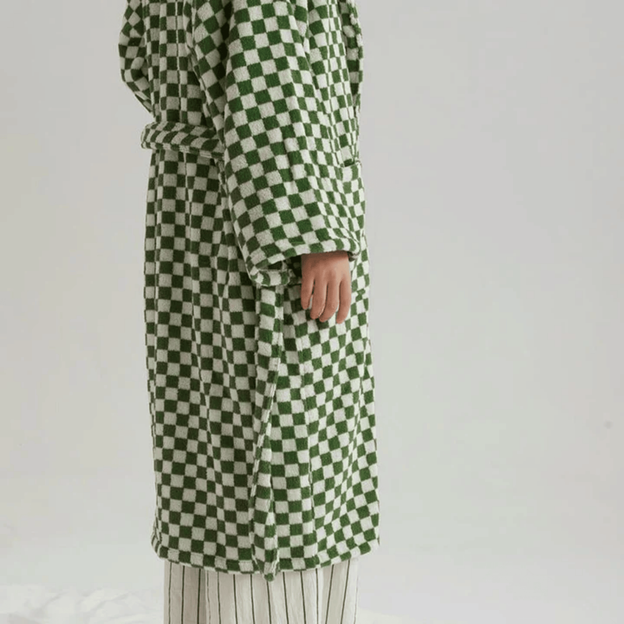 Green and white checkered coat worn by a person on a plain background