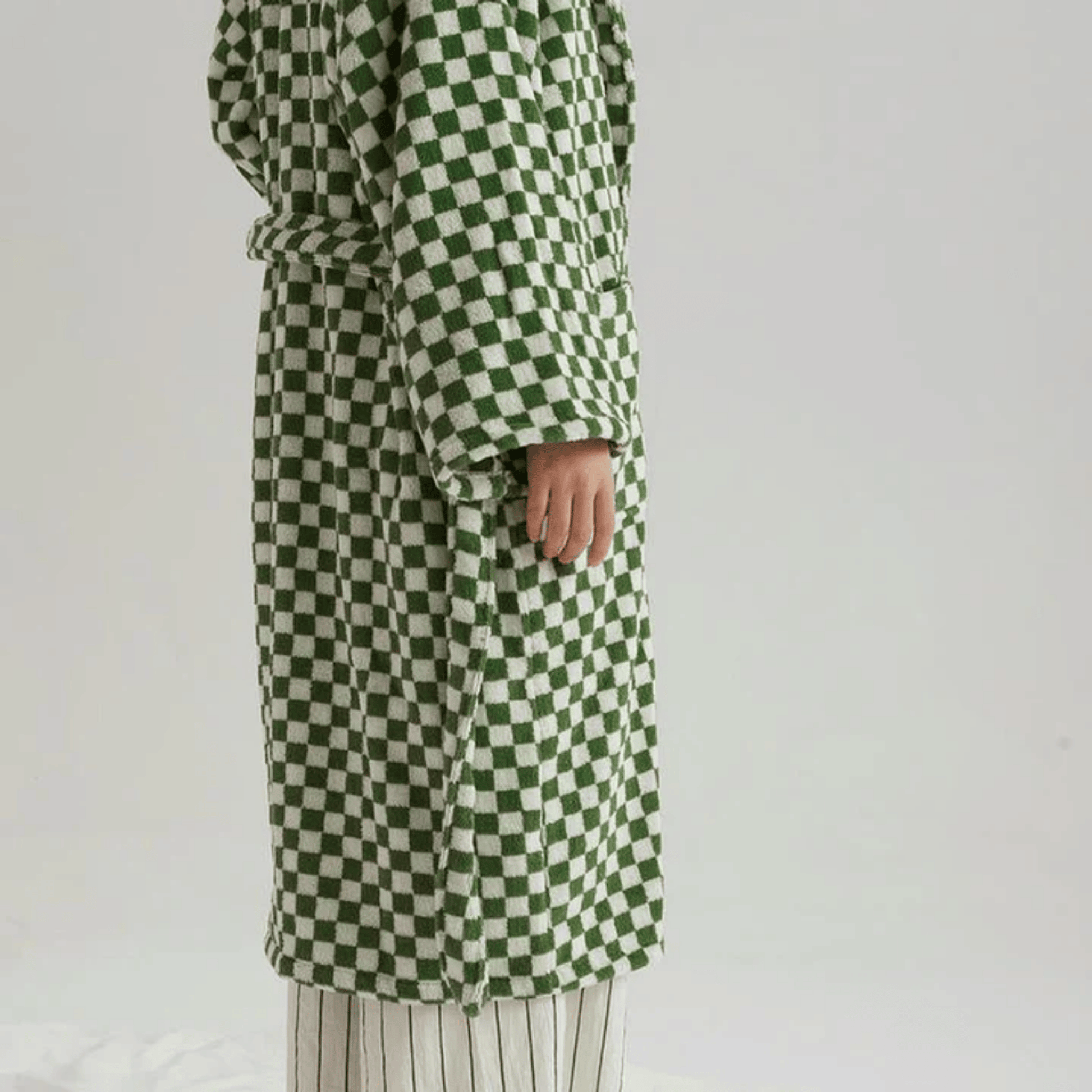 Green and white checkered coat worn by a person on a plain background