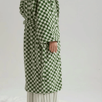 Green and white checkered coat worn by a person on a plain background