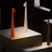 Three modern table lamps in orange, white, and brown on a black background