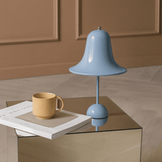 Blue lamp and yellow mug on a glass table with a brown background