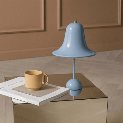 Blue lamp and yellow mug on a glass table with a brown background