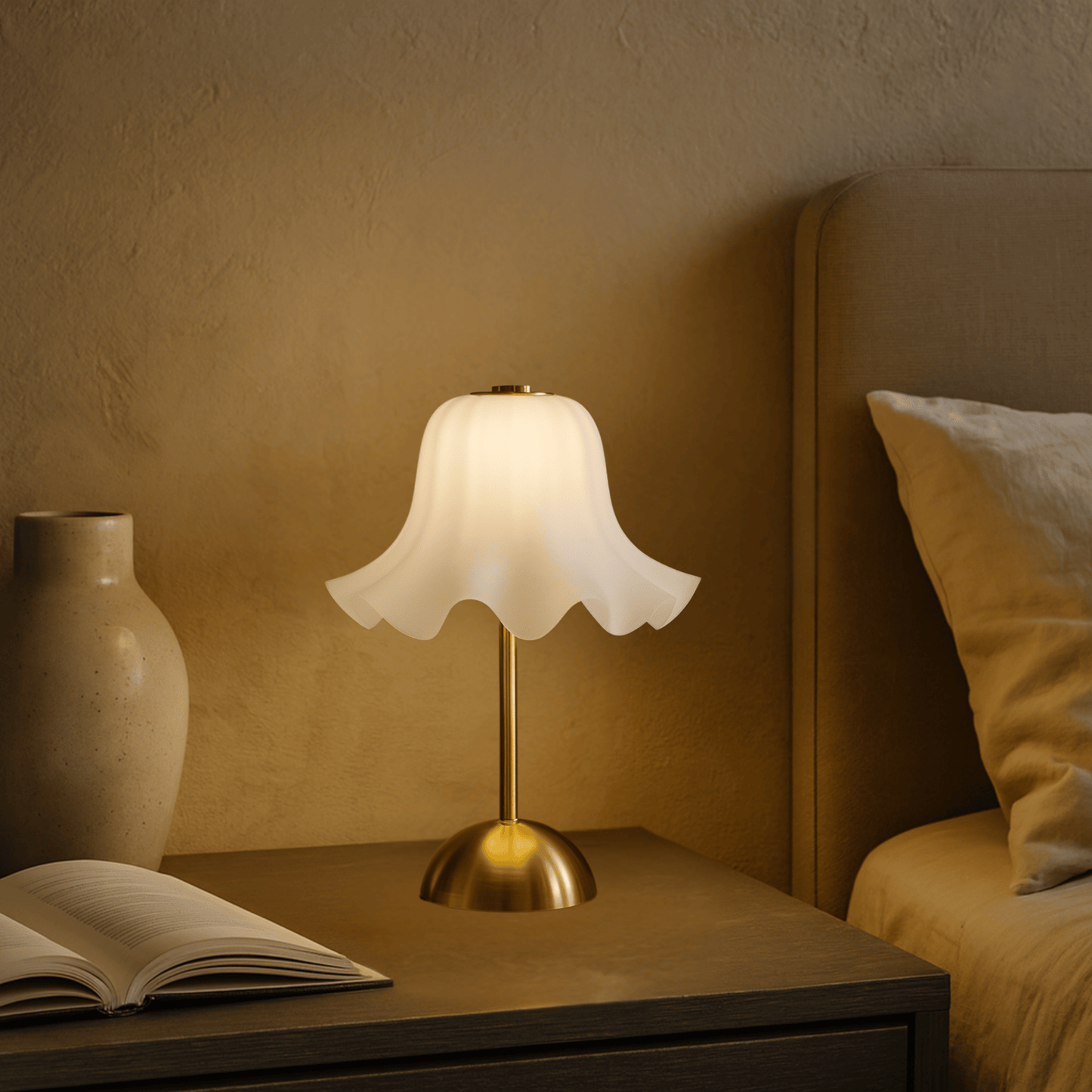 Table lamp on a nightstand next to an open book and a vase, with a warm glow.