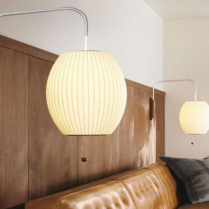 Modern pendant light fixture hanging above a sofa in a room with wooden paneling.