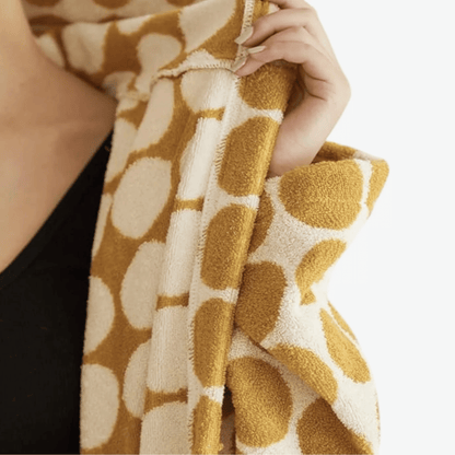 Close-up of a hand holding a textured fabric with a pattern, on a neutral background.
