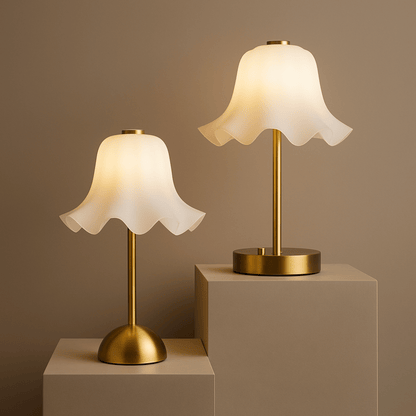 Two table lamps with white lampshades and gold bases on beige pedestals against a brown background.