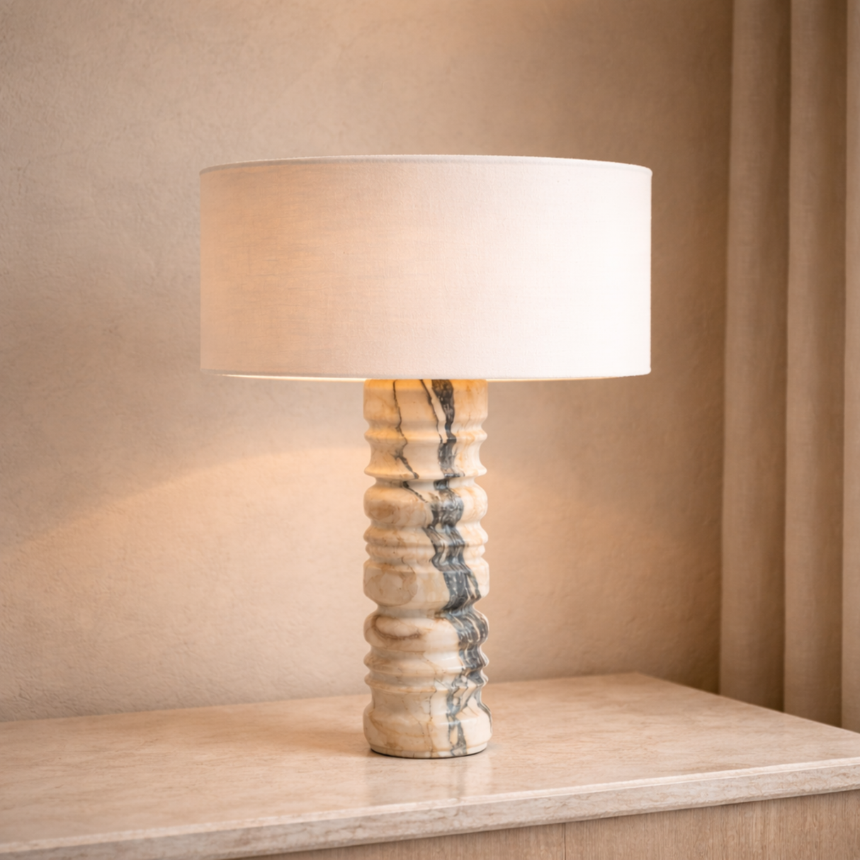 Table lamp with a marble base and beige shade on a wooden surface.