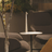 Modern outdoor seating area with a small table and chairs, featuring a plant in the background.