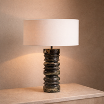 Table lamp with a textured black base and white shade on a wooden surface.