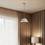 Decorative pendant light hanging in a room with curtains and a lamp.